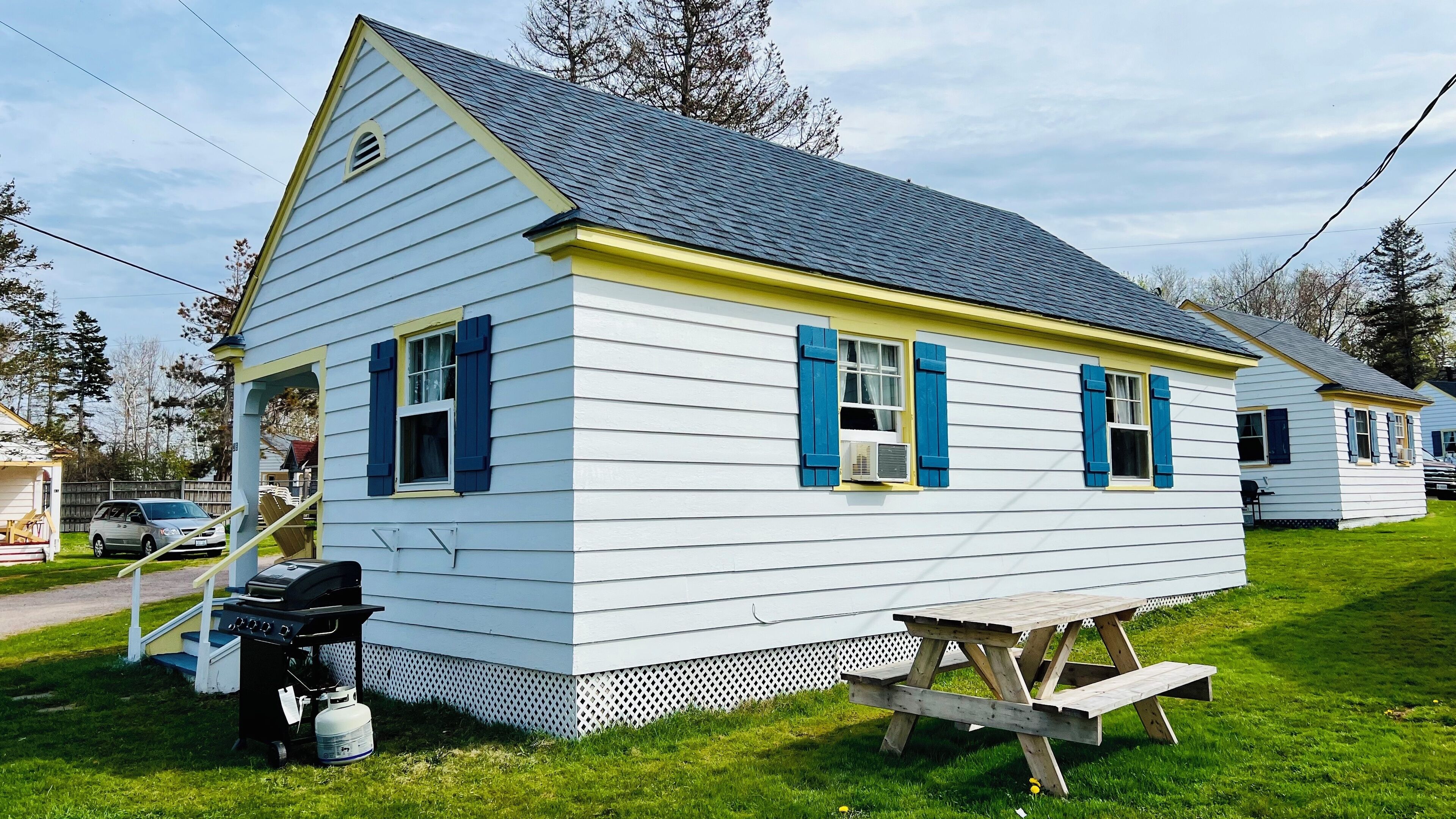 A white house with blue shutters and a grey roof.