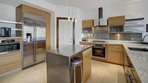 A modern kitchen with stainless steel appliances, wooden cabinets, and a granite countertop. - Osprey 303 (Avon)
