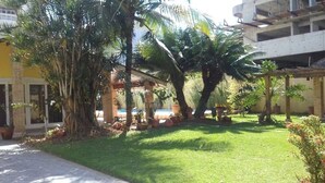 A courtyard with palm trees, a brick building, and a pool. - Hostel Brazil Backpackers (Guarujá)