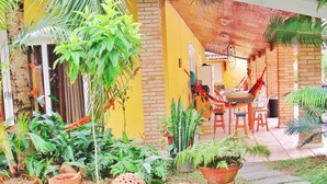 A patio area with a hammock, outdoor seating, and various potted plants. - Hostel Brazil Backpackers (Guarujá)