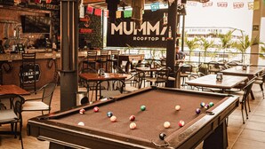 A billiards table in a restaurant with a thatched roof and wicker furniture. - Nomads Hotel & Rooftop pool (Cancun)