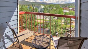 Un balcon avec une balustrade rouge, deux chaises et une table.