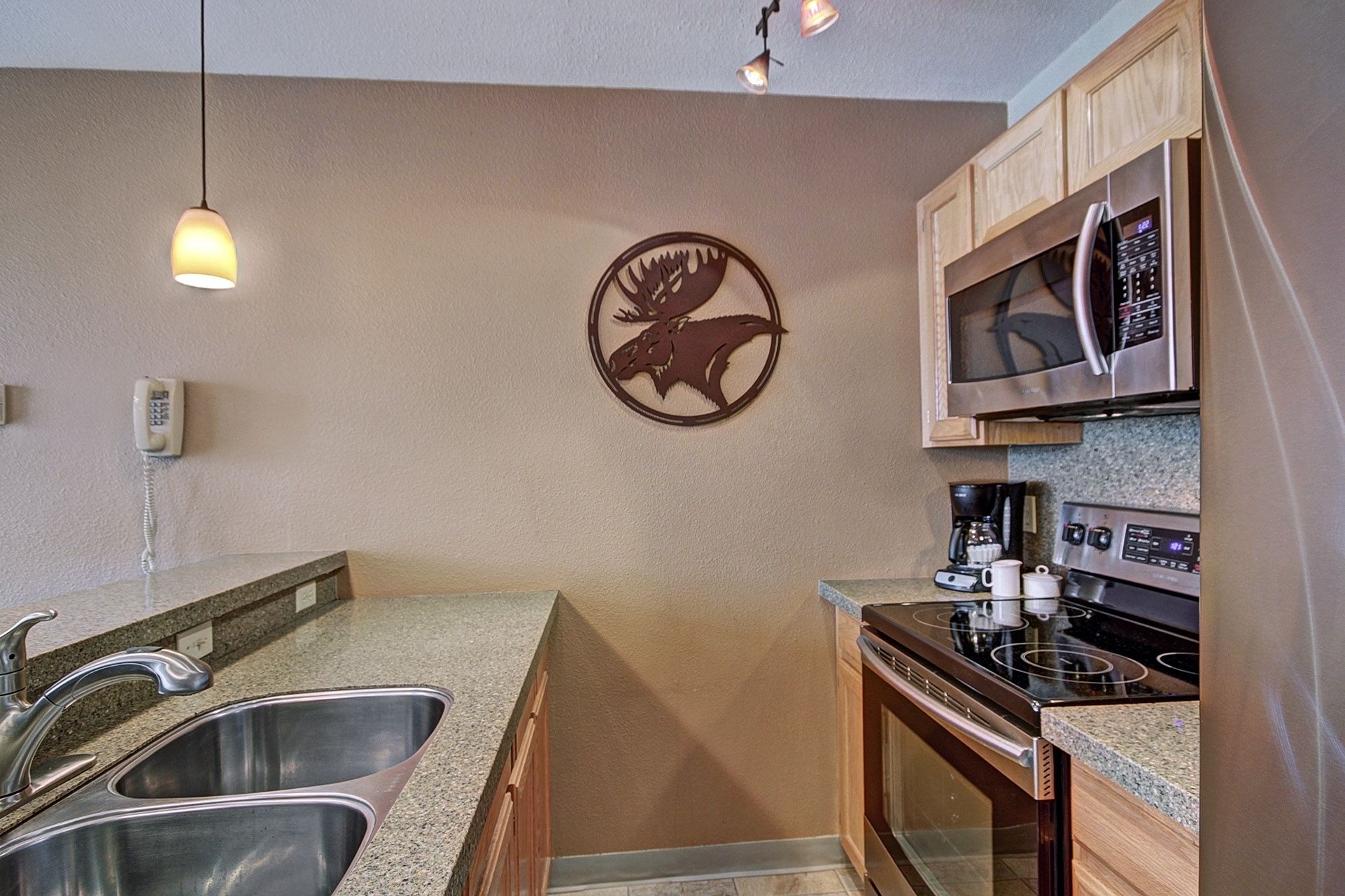 A modern kitchen with stainless steel appliances, a double sink, and wooden cabinets.