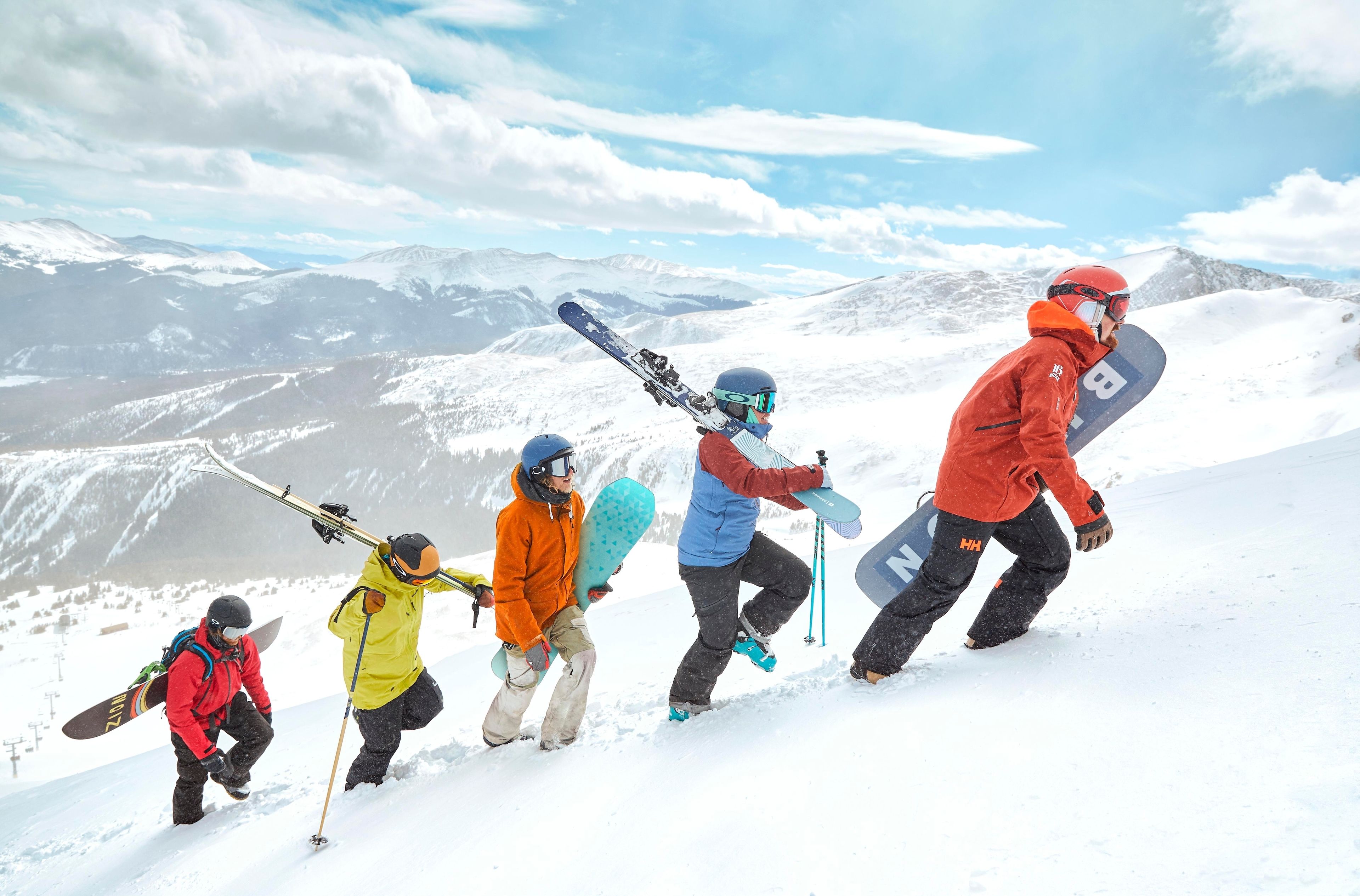 A group of skiers ascending a snowy mountain with a clear sky.
