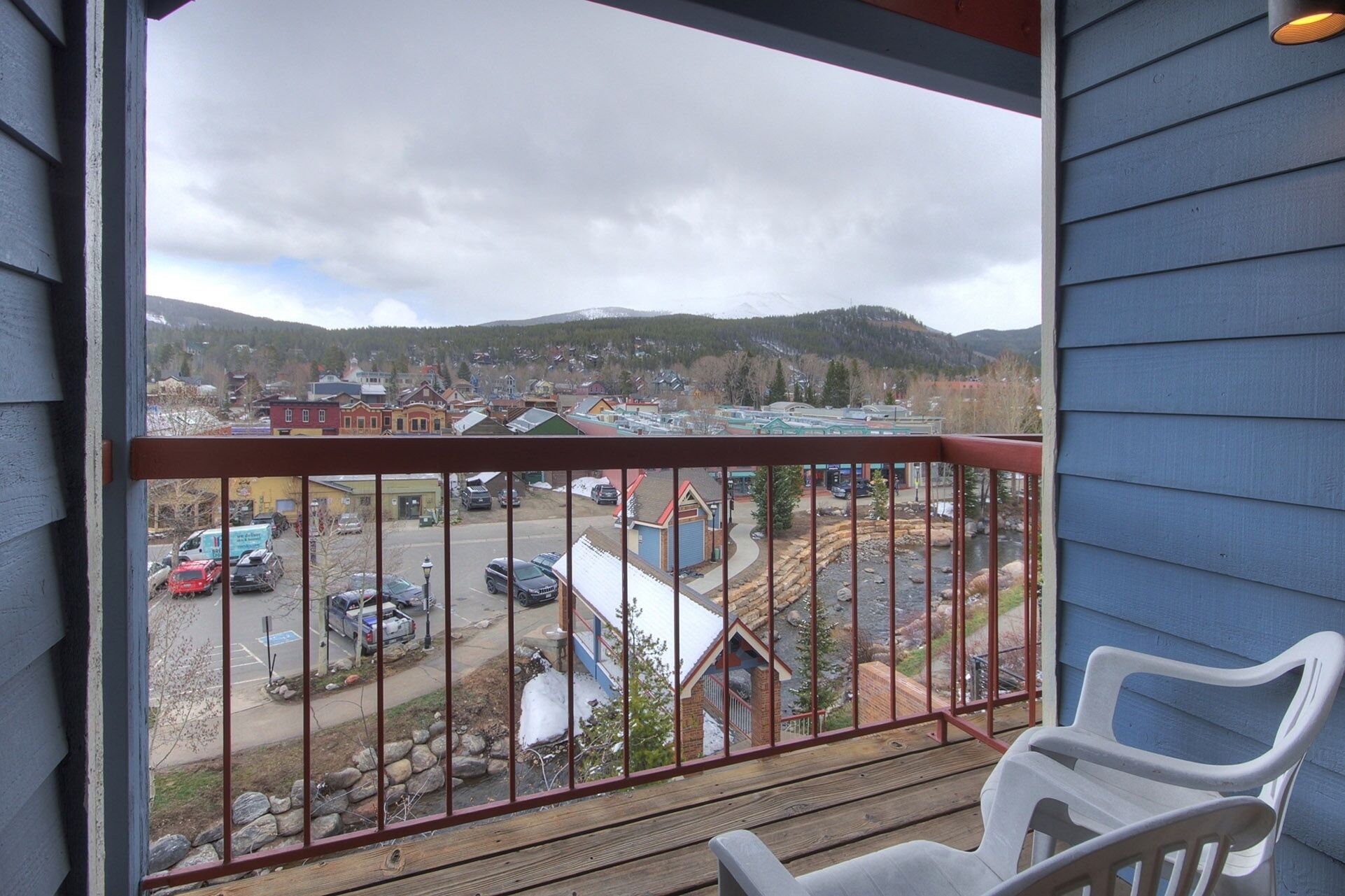 A balcony with a view of a town, a parking lot, and a river.