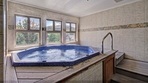 Ein Spa-Raum mit Whirlpool, großen Fenstern und Blick auf Bäume.