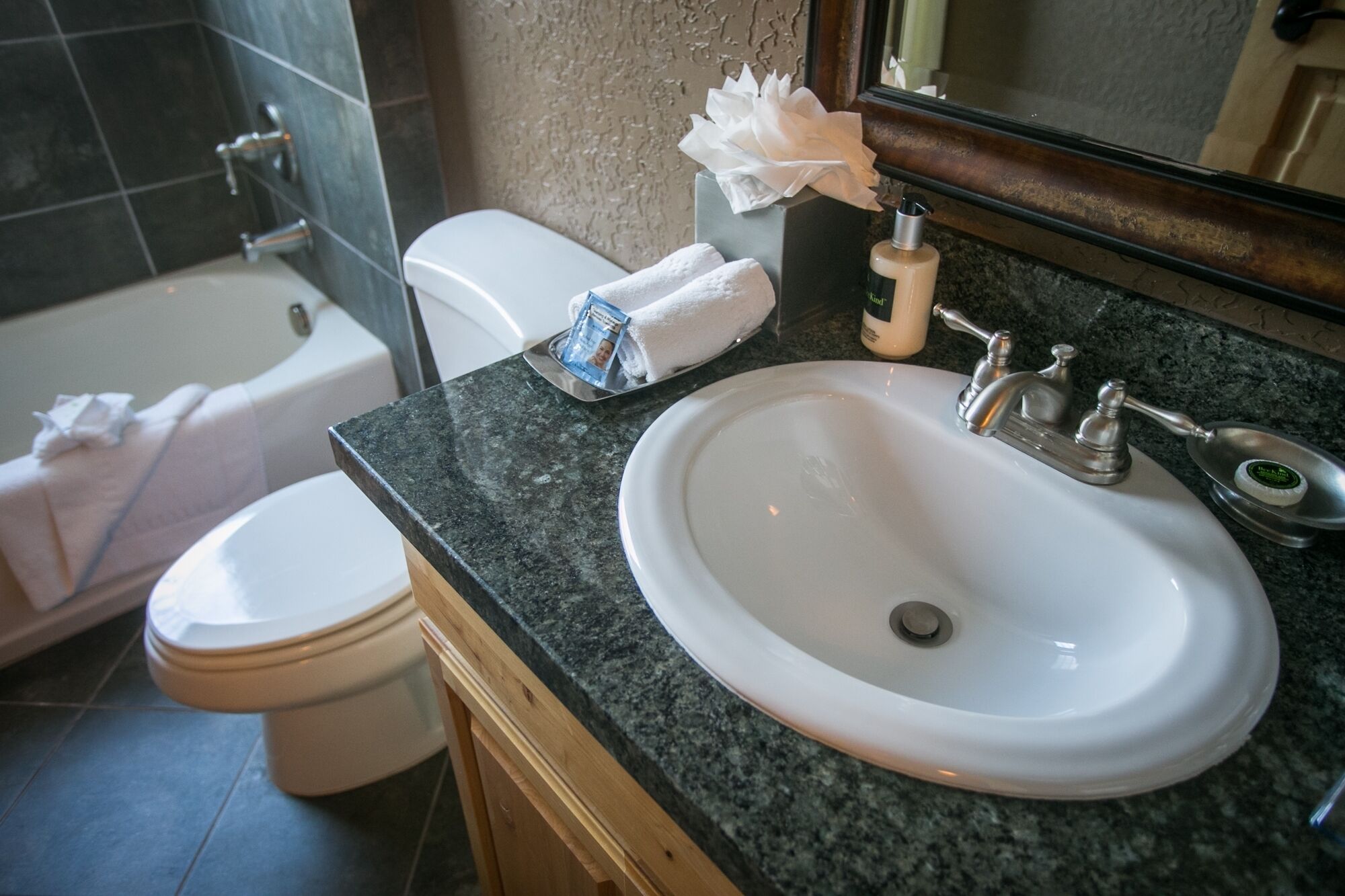 A bathroom with a white sink, a mirror, a towel, and a bottle of soap.
