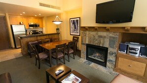 A living room with a fireplace, a dining area, and a kitchen. - Rustic Lofted Steps from Mountain Adventure by RedAwning (Park City)