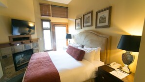 A hotel room with a bed, a TV, a fireplace, and a desk with a phone. - Rustic Lofted Steps from Mountain Adventure by RedAwning (Park City)