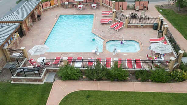 A swimming pool with multiple sun loungers and a hot tub area, surrounded by a fenced patio with outdoor seating. - Rustic Lofted Steps from Mountain Adventure by RedAwning (Park City)