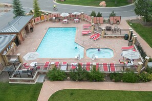 Ein Schwimmbecken mit mehreren Liegestühlen und einem Whirlpool-Bereich, umgeben von einer eingezäunten Terrasse mit Sitzgelegenheiten.