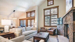 A spacious living room with a fireplace, large windows, and a cozy seating area.