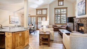 A spacious living area with a fireplace, wooden furniture, and large windows.