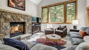 A living room with a stone fireplace, large windows, a sofa, and a coffee table.