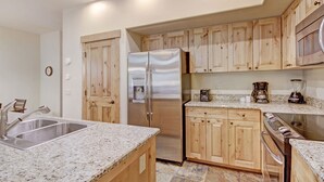 Una cocina con encimeras de granito, electrodomésticos de acero inoxidable, armarios de madera y horno empotrado.