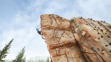A person climbing a large rock wall with climbing holds.
