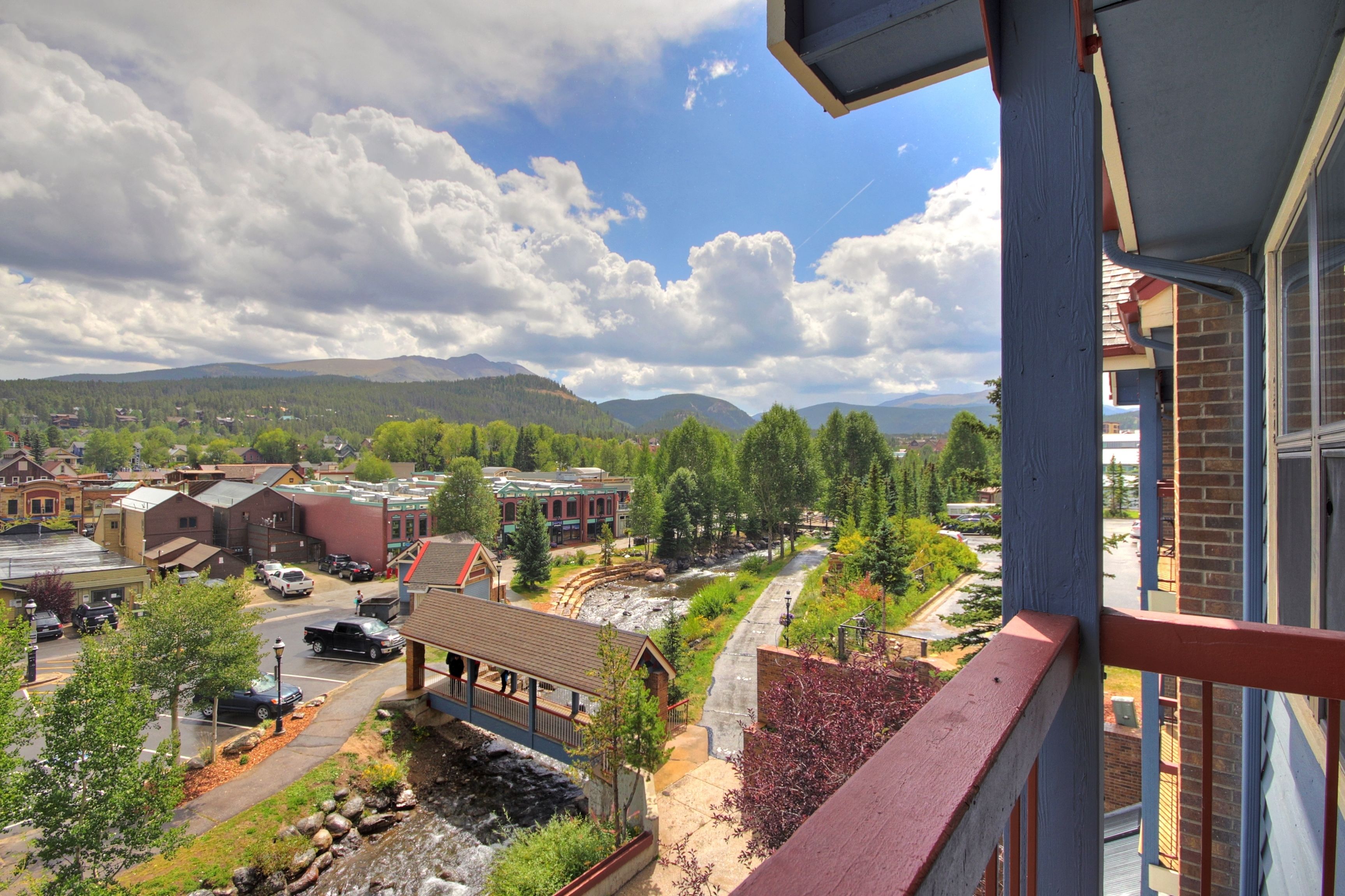 A view of a town with buildings, a river, and mountains in the background.