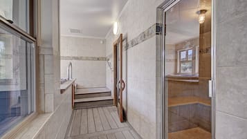 Bathroom features a shower area with a glass door, bench, and small window.