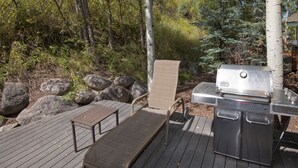 An outdoor deck with a grill, a chair, and a table. - Arrowhead 254 (Edwards)