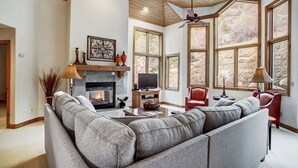 A spacious living room with a large gray sectional sofa, a fireplace, a television, and a red chair. - Arrowhead 254 (Edwards)