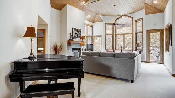 A spacious living room with a grand piano, a comfortable sofa, and large windows offering views of the outdoors. - Arrowhead 254 (Edwards)