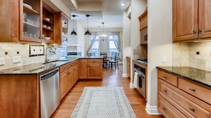 A kitchen with wooden cabinets, a dishwasher, and a dining area with a chandelier. - Luxury 4 Bedroom Home in Central Austin (Austin)