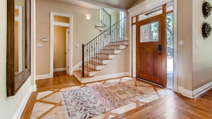 A spacious foyer with a wooden staircase, a patterned rug, and a wooden door. - Luxury 4 Bedroom Home in Central Austin (Austin)