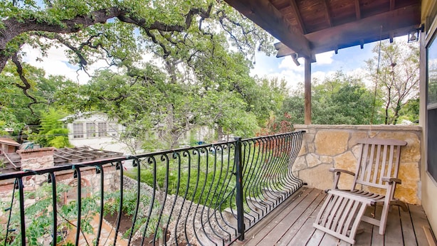 A wooden deck with a stone wall and a wooden chair. - Luxury 4 Bedroom Home in Central Austin (Austin)