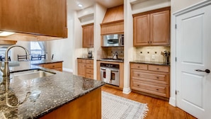 A modern kitchen with wooden cabinets, stainless steel appliances, and a granite countertop. - Luxury 4 Bedroom Home in Central Austin (Austin)