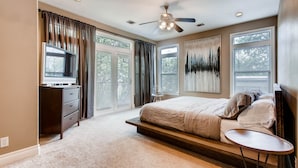 A bedroom with a bed, a desk, a ceiling fan, and large windows. - Luxury 4 Bedroom Home in Central Austin (Austin)