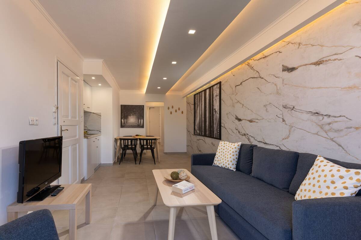 A modern living room with a sofa, a coffee table, and a TV.