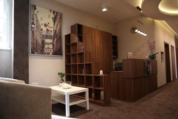 A modern interior with a white table, a wooden bookshelf, and a framed cityscape painting.