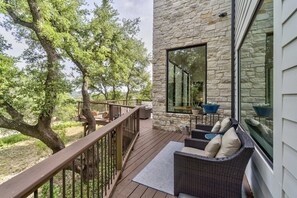 Ein Balkon mit Korbmöbeln, einer Steinwand und Blick auf Bäume.