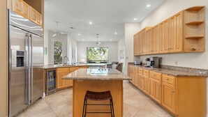 Une cuisine moderne avec des meubles en bois, des appareils en acier inoxydable et un grand îlot central doté de sièges.