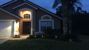 Una casa de dues plantes amb garatge, un porxo i una palmera.