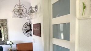 Ein modernes Wohnzimmer mit einem braunen Ledersofa, einem blauen Sessel, einem kleinen Beistelltisch mit einer Blumenvase, einer Dekoklocke und einer Chandelieber.