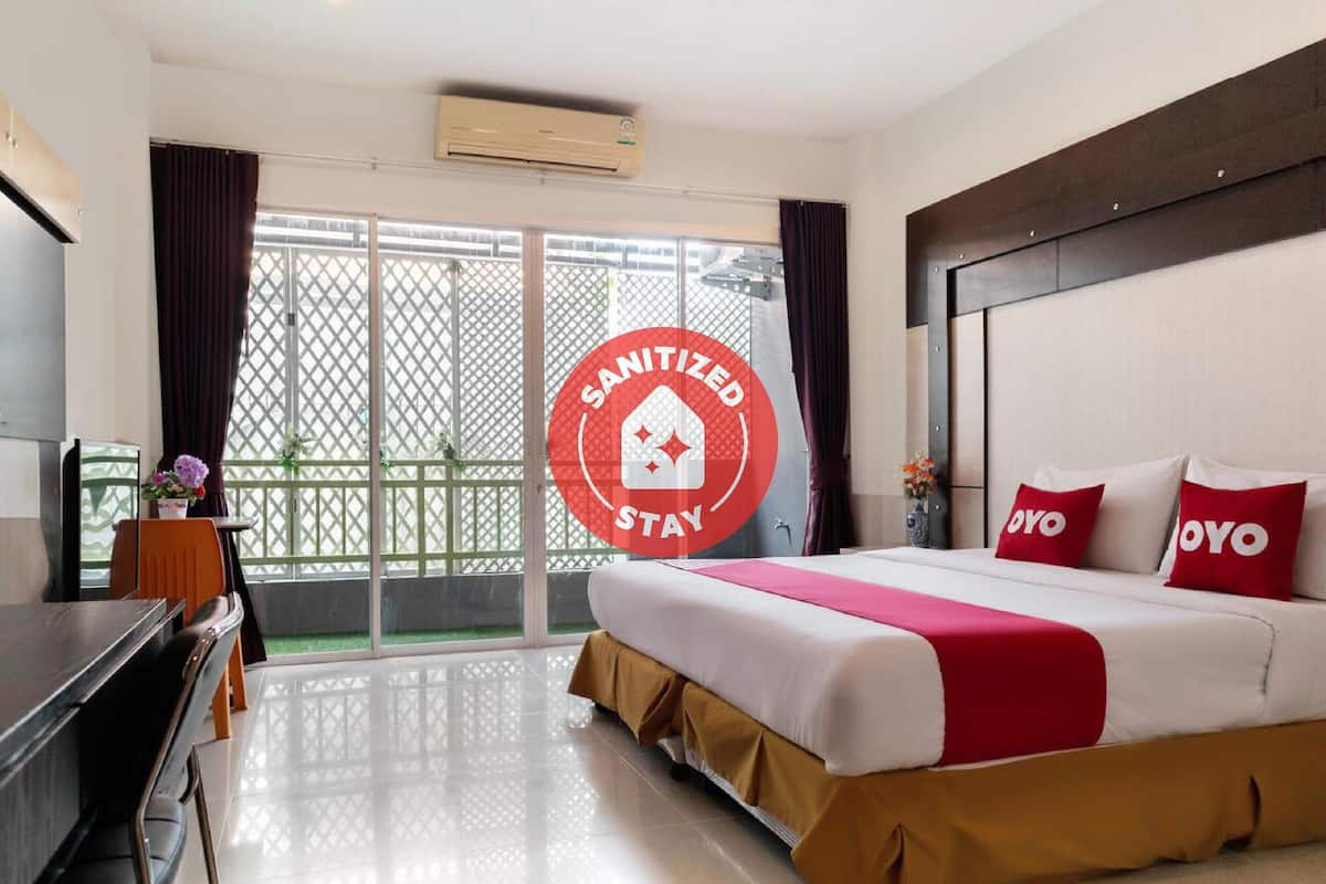 Habitación de hotel con cama, escritorio y vista a un espacio exterior verde.