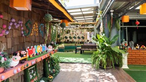 A courtyard with a wooden bench, a welcome sign, and various plants. - OYO 792 Omsaga Phuket Hotel (Ratsada)