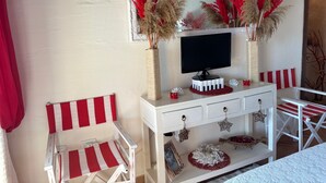 Une pièce avec un meuble TV blanc, une chaise à rayures rouges et blanches et des plantes décoratives.