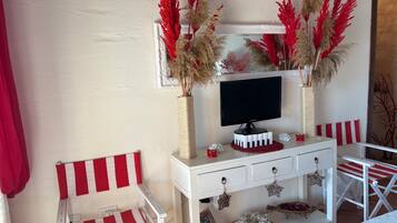 Une pièce avec un meuble TV blanc, une chaise à rayures rouges et blanches et des plantes décoratives.