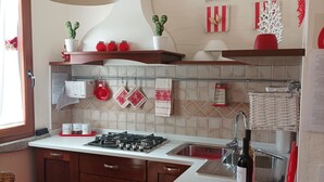 Une cuisine moderne avec des meubles en bois, une cuisinière à gaz, un évier et un luminaire suspendu.