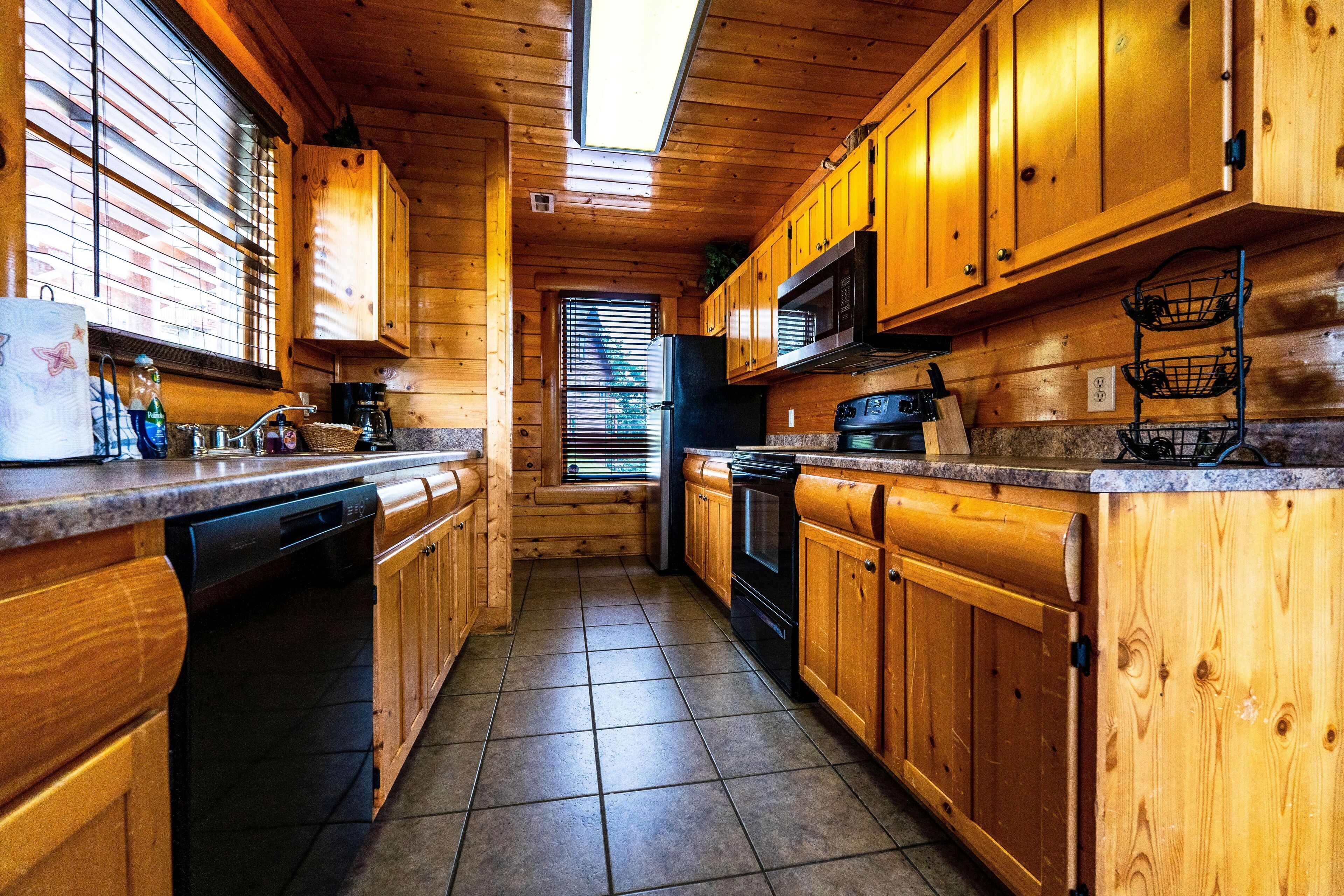 Une cuisine rustique, située dans une cabane en bois, équipée d’un lave-vaisselle, d’une cuisinière et d’un four à micro-ondes.