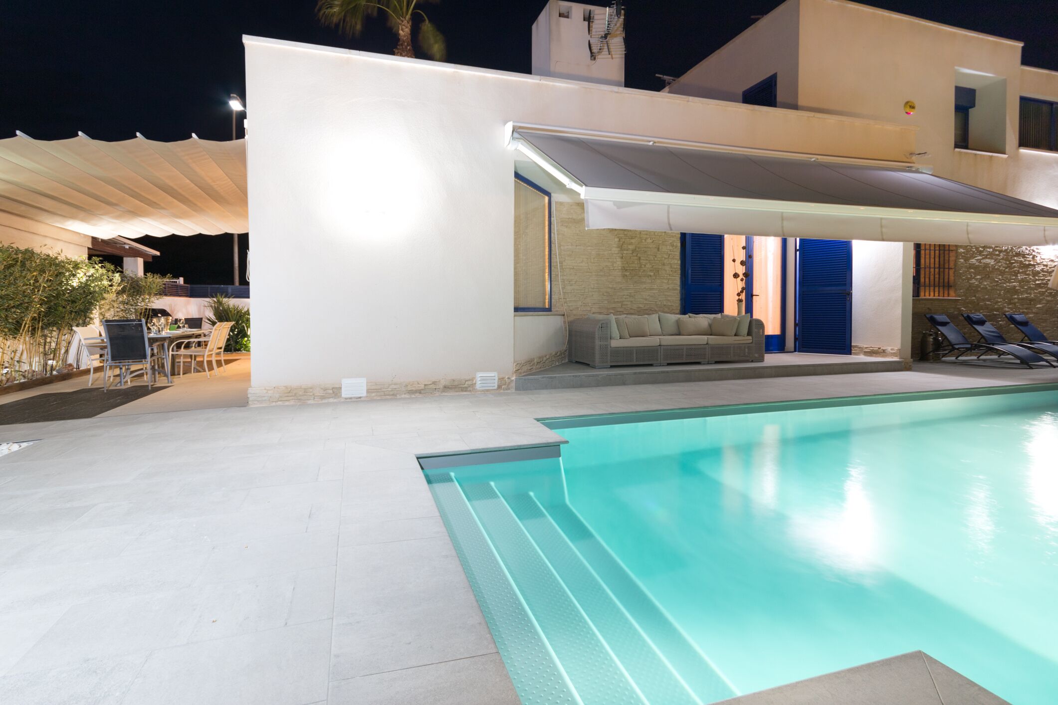 A modern outdoor pool area with a covered seating area and lounge chairs.