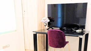Una habitación con una cama, un escritorio con una computadora y una silla.