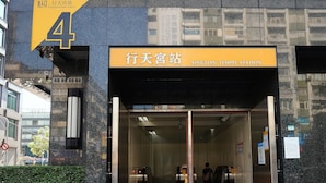 La entrada a la estación Xingtian Temple con una puerta de cristal transparente, un cartel que indica la entrada y un edificio adyacente con el número 4 visible.