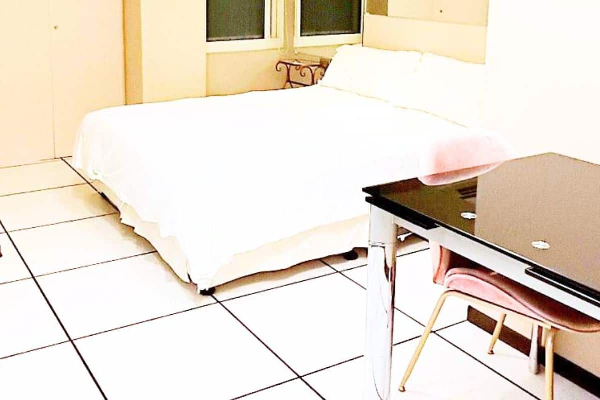 A bedroom with a bed, a desk, and a chair.