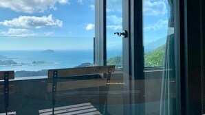 Une pièce dotée d’une grande porte vitrée donnant sur un balcon d’où l’on peut admirer l’océan et les îles au loin.