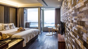 Une chambre d’hôtel moderne avec un grand lit, un petit bureau, une chaise et une vue sur les montagnes par la fenêtre.