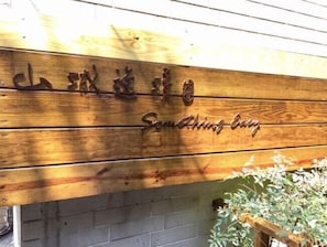 A wooden sign with carved text and a metal emblem, mounted on a wall.