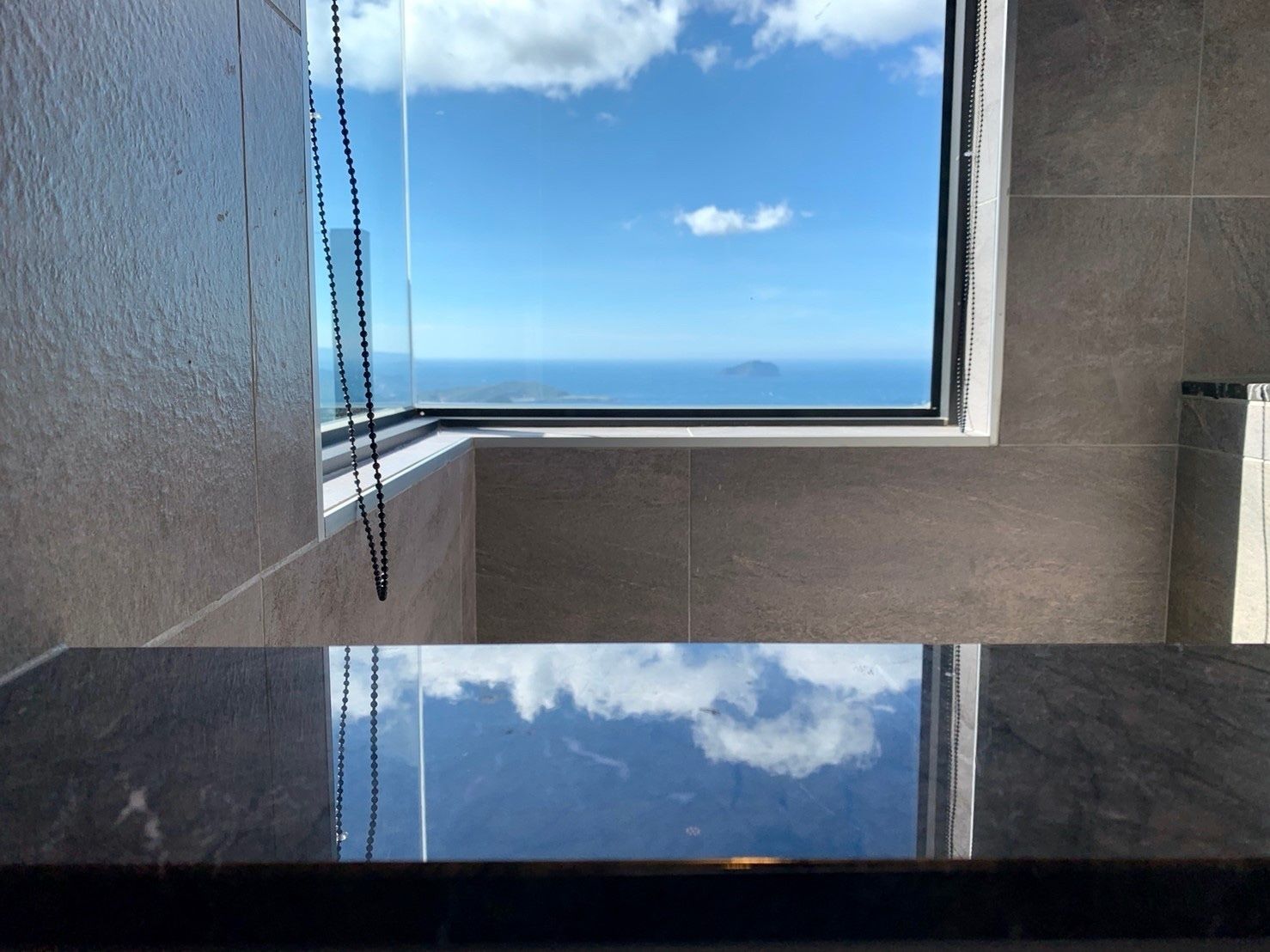 A corner of a room with a view of the sea through a window.